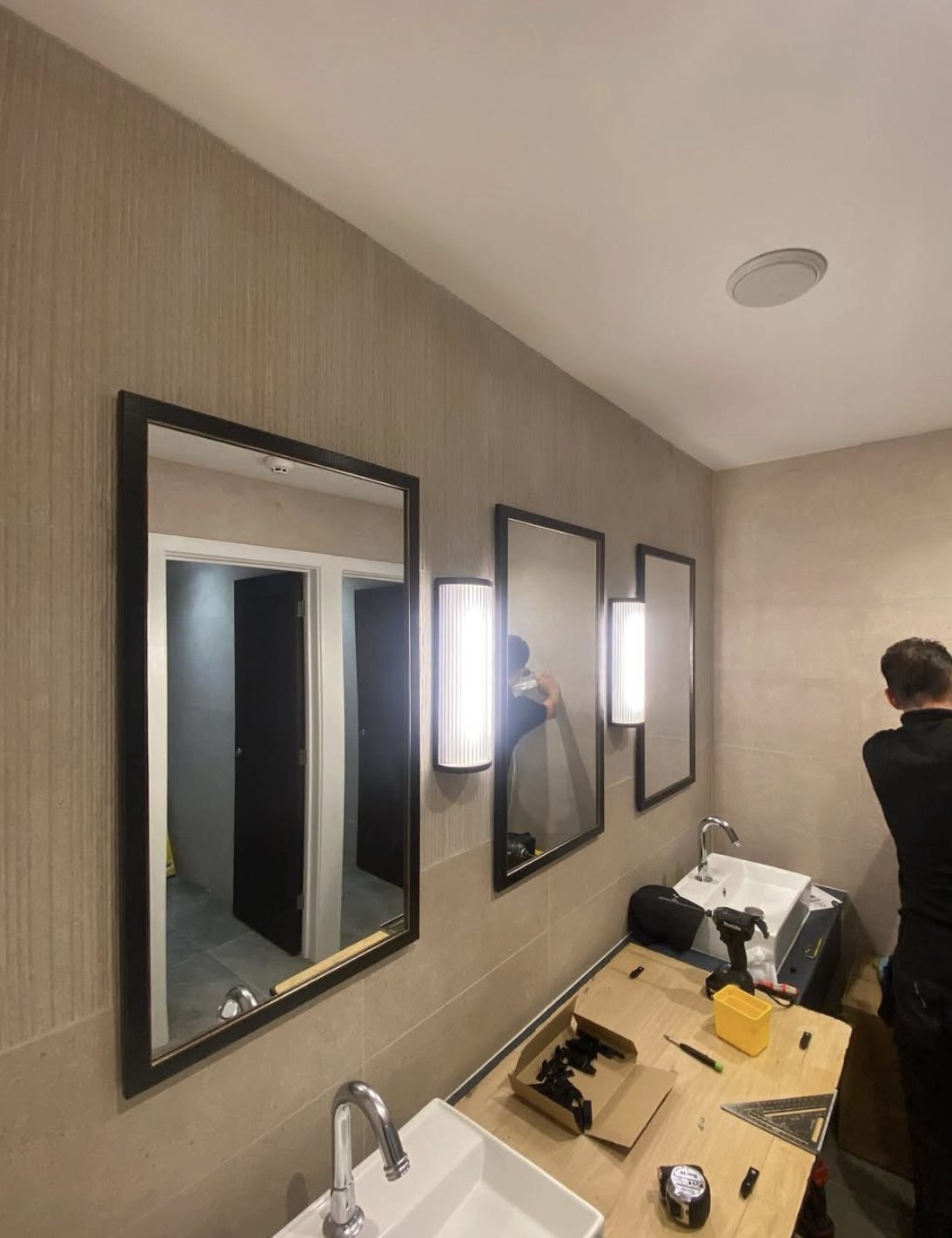 Wall lights and mirrors being installed in a washroom refurbishment