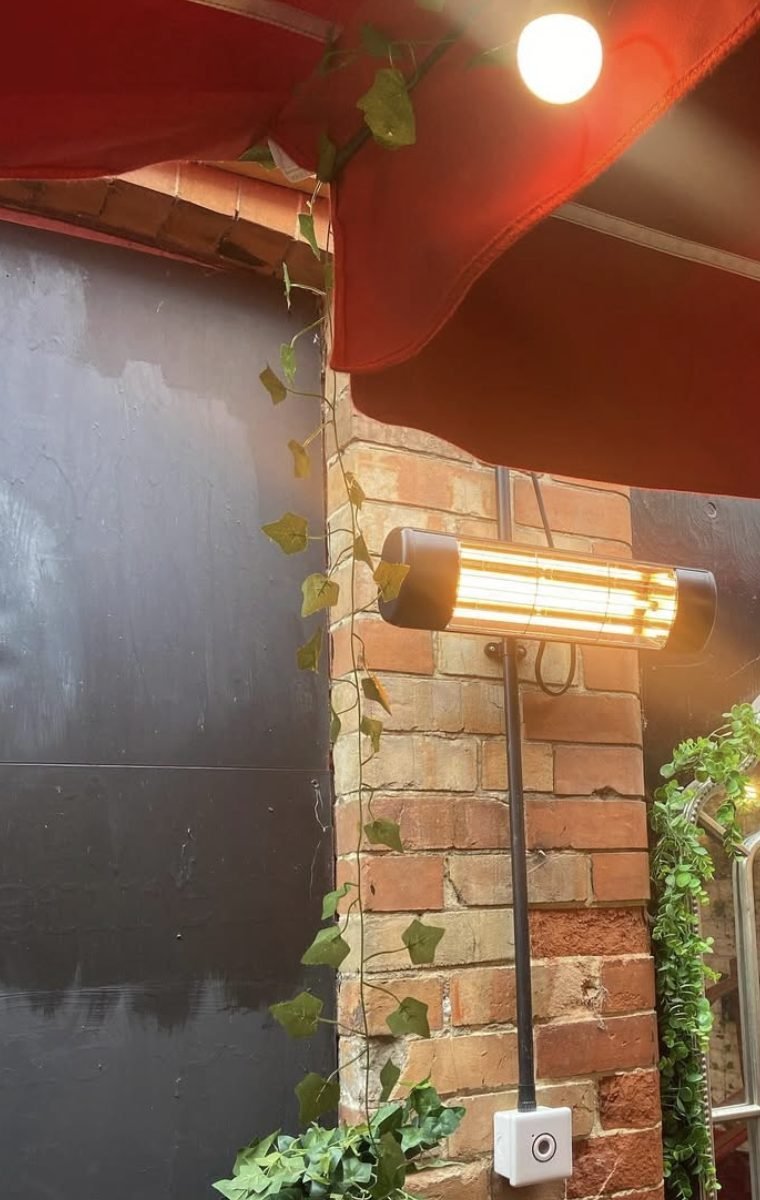 Infrared patio heater fixed to brickwork beneath an awning